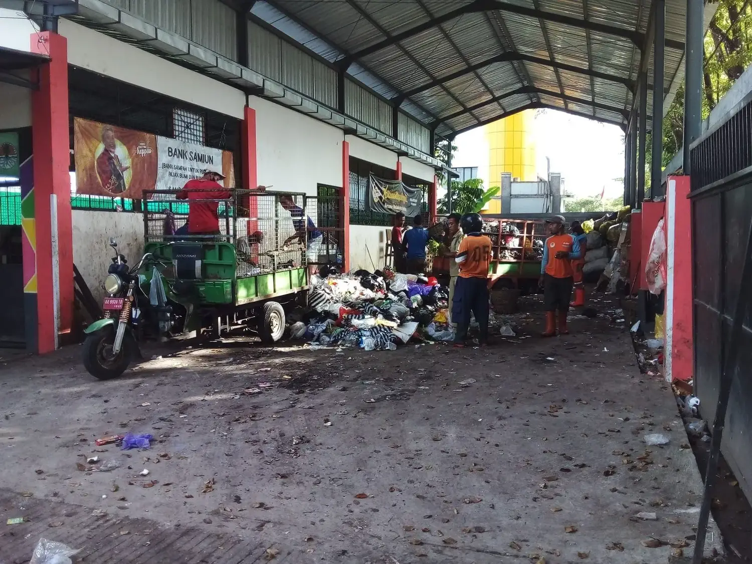 Petugas bank sampah bekerja di antara tumpukan material yang sudah dipilah.