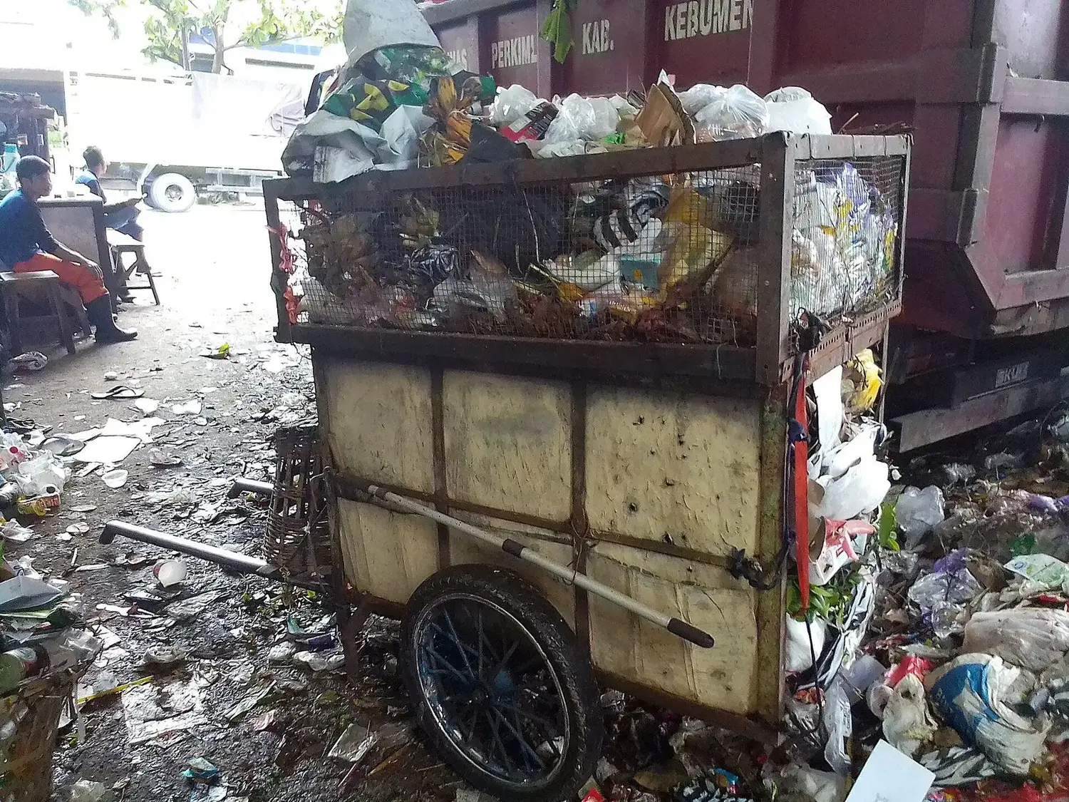 Gerobak sampah penuh melintas di sebuah gang permukiman.